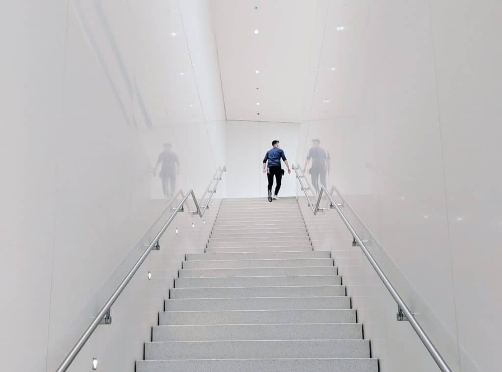 Man walking up stairs in white hallway