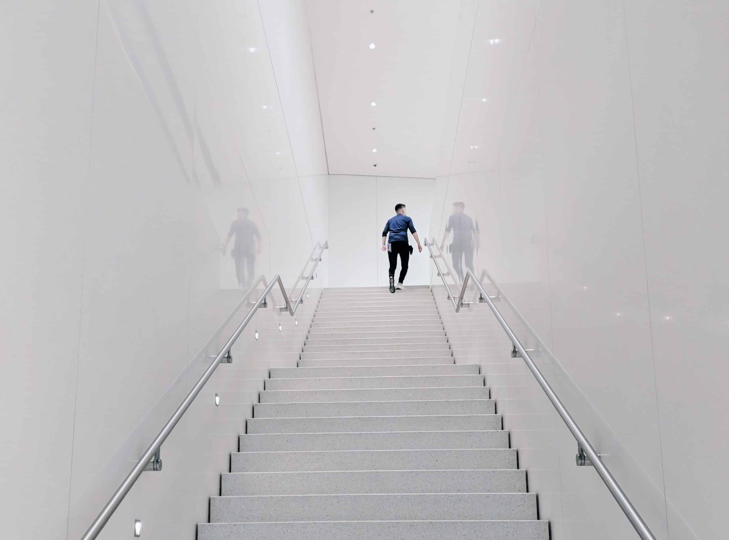 Man walking up stairs in white hallway