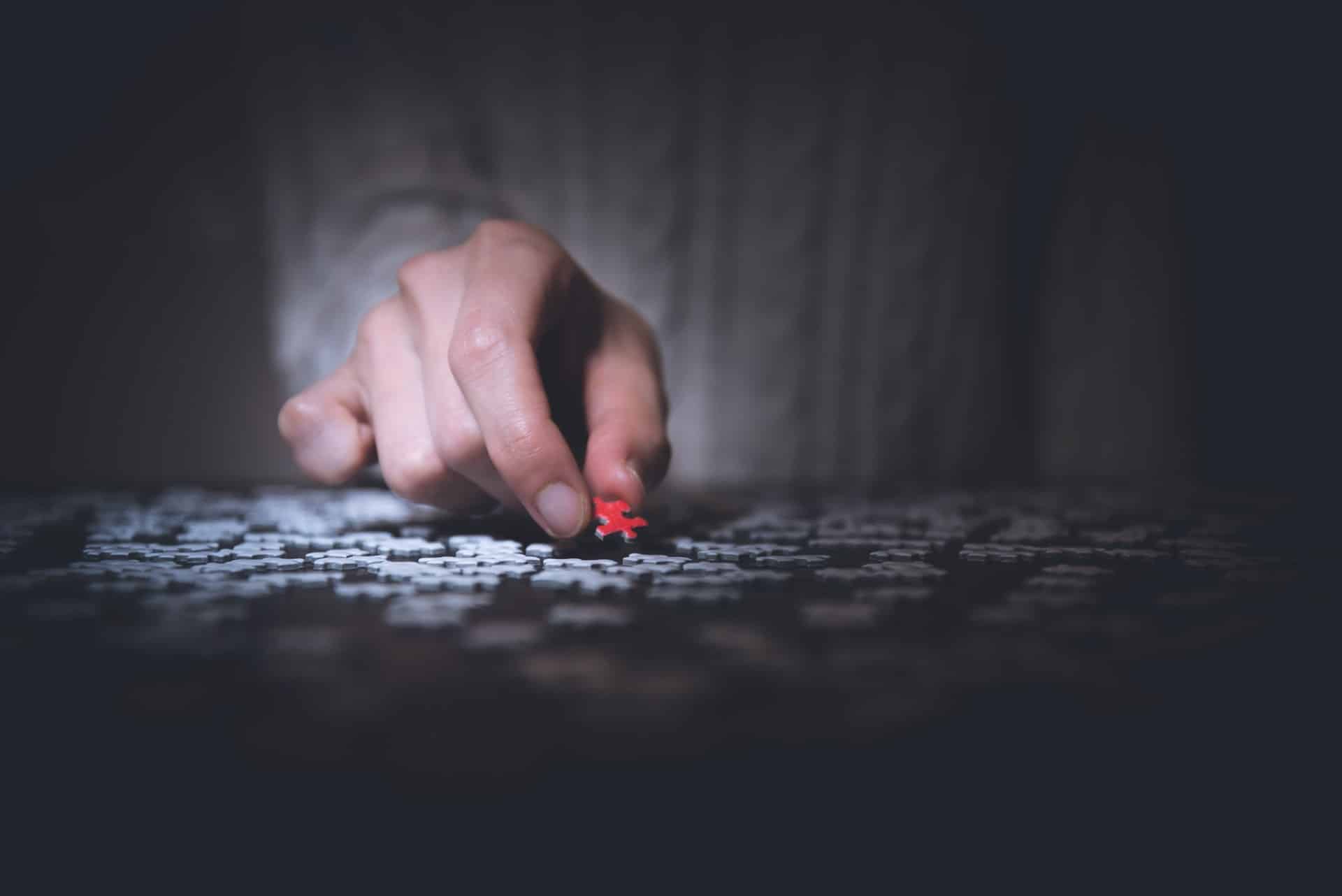 Hand Placing Red Puzzle Piece In Place
