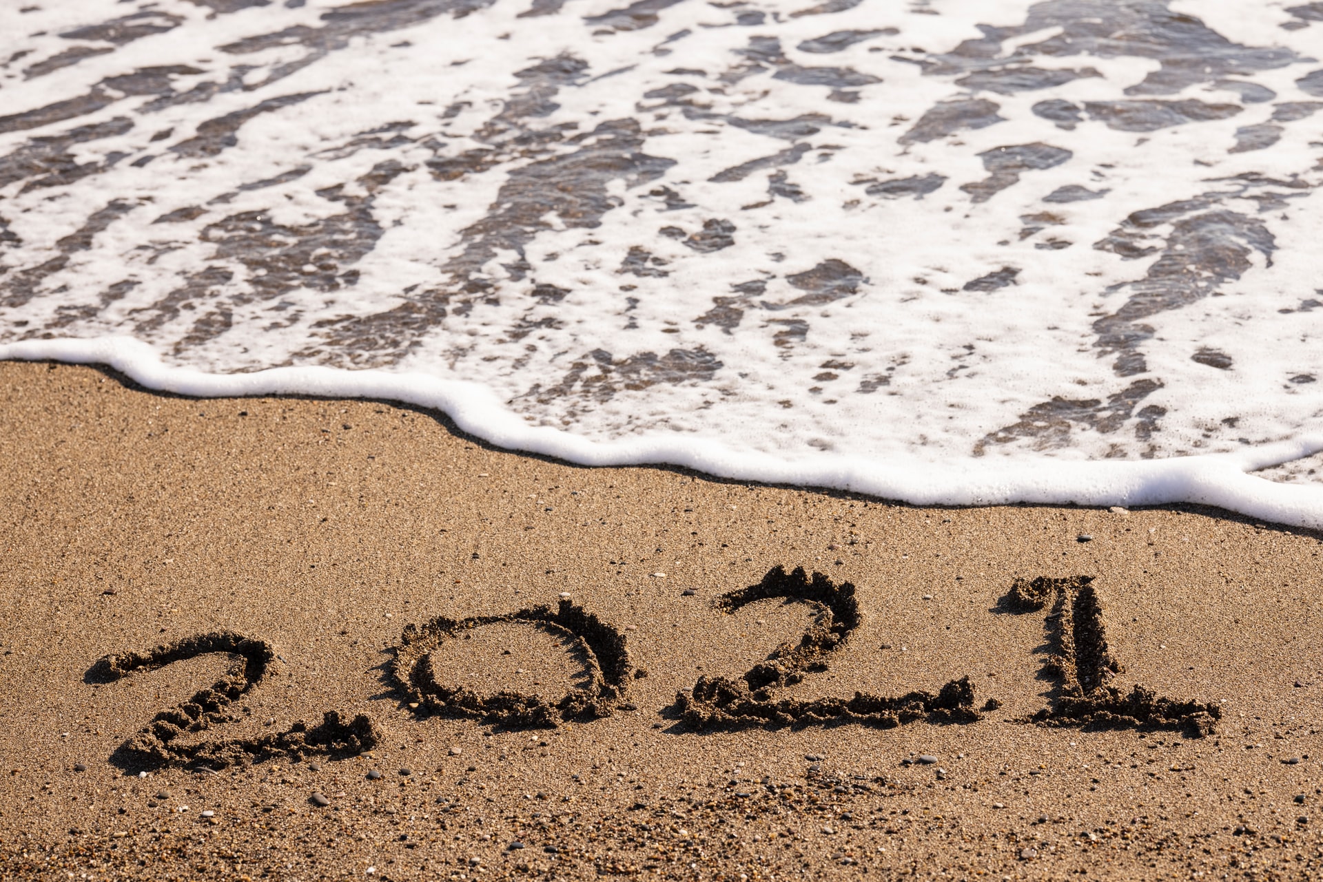 Water washing up on a beach with the year in the sand